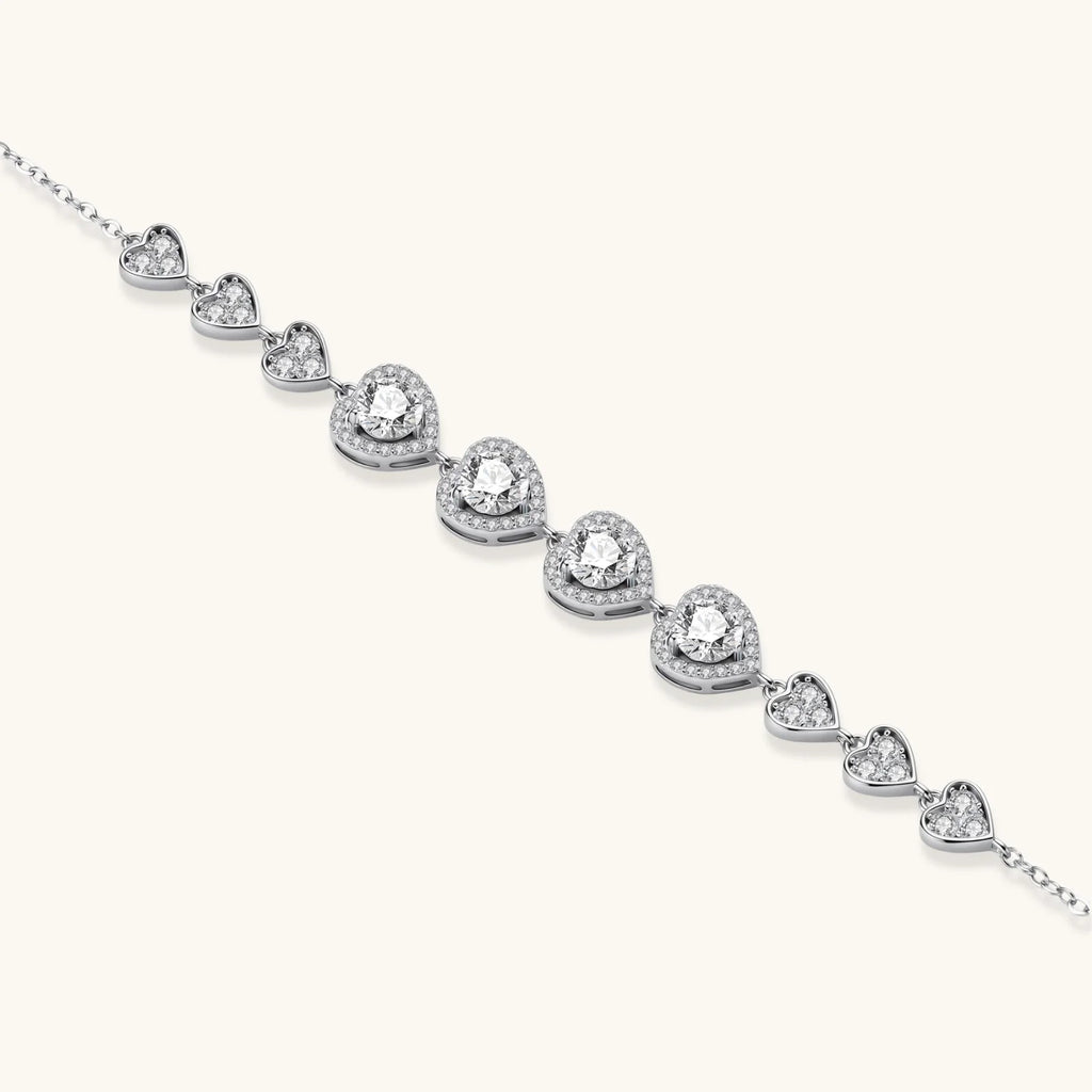 Sterling silver bracelet with graduated heart-shaped links and sparkling moissanite stones in VVS1 clarity on white background.