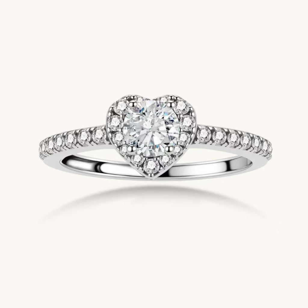 Heart-shaped halo ring with brilliant moissanite center stone surrounded by smaller crystals in sterling silver setting