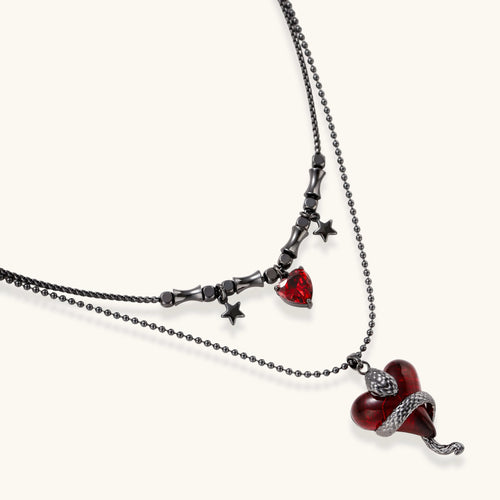 Dark layered necklace set with black chains and red heart pendants, featuring gothic snake design on white background