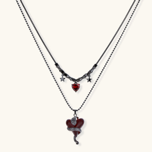 Dark layered necklace set with black chains and red heart pendants, featuring gothic snake design on white background