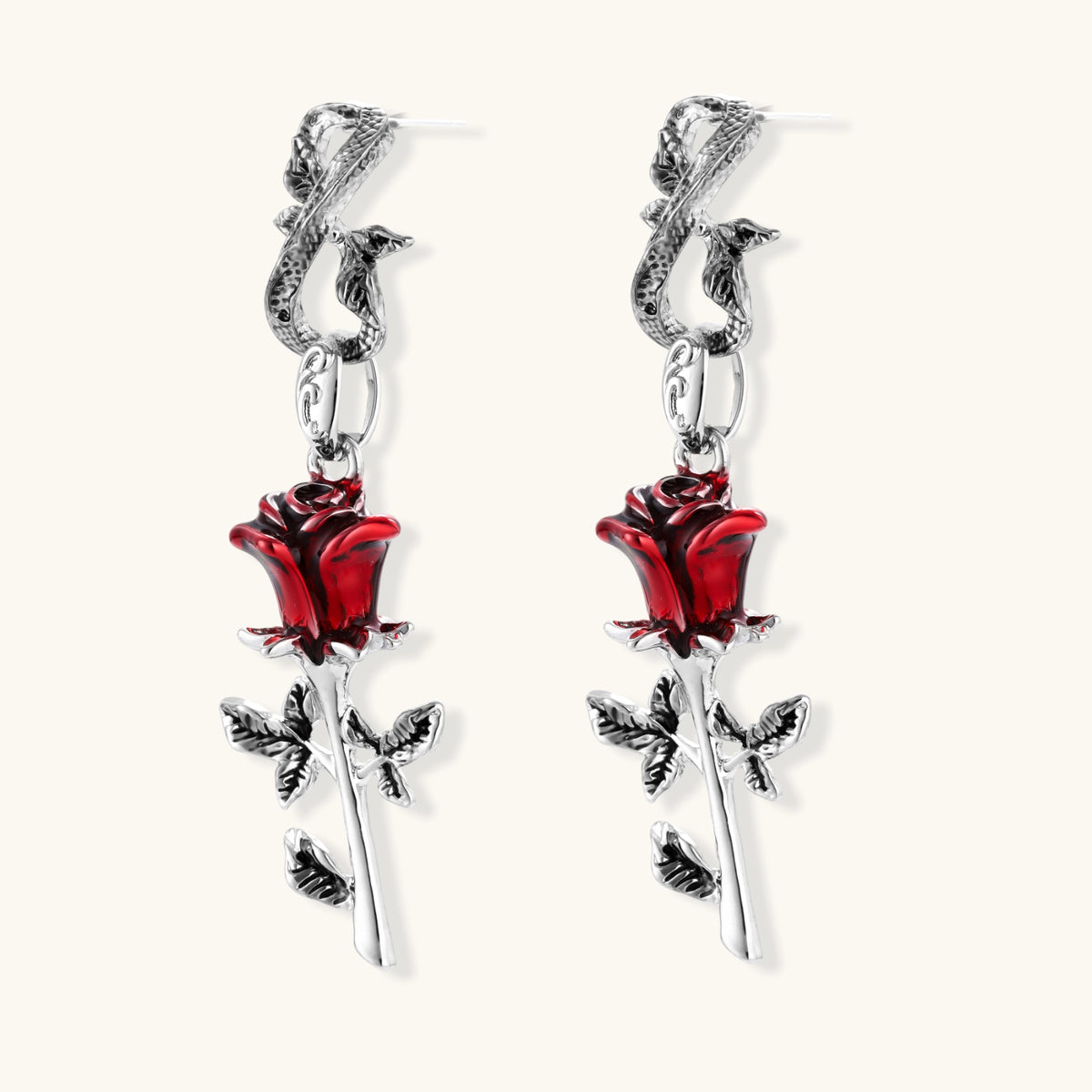Gothic dangle earrings featuring silver serpent hooks with red enamel roses and metallic stems on white background.
