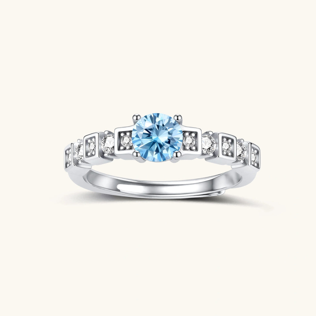 Geometric sterling silver ring with light blue moissanite center stone and square diamond accents on white background
