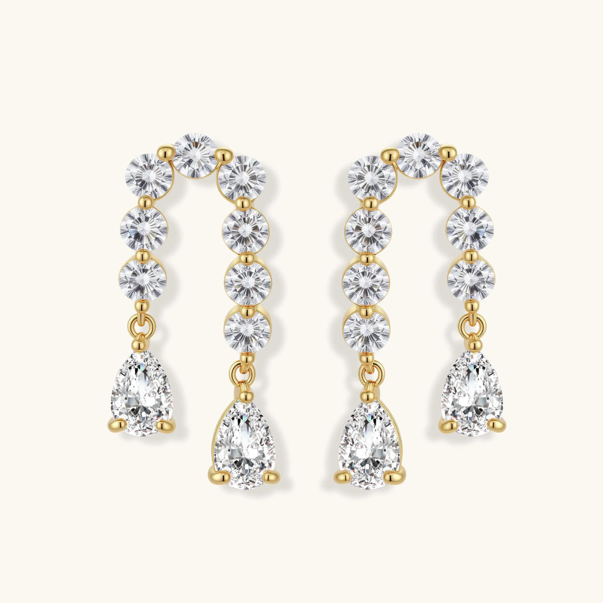 Gold-plated earrings with vertical line of clear crystals and teardrop pendants on neutral background