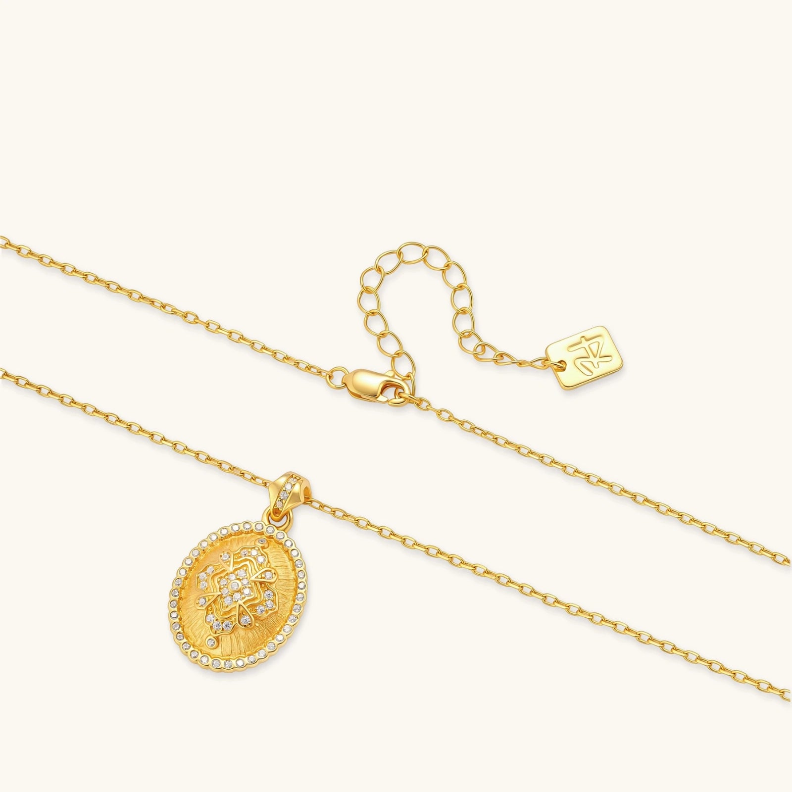 Oval gold coin pendant with pave CZ mandala motif and beaded border on an 18K gold-plated cable chain.