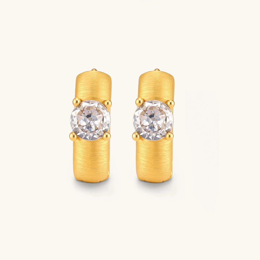 18K gold-plated 925 silver huggie hoops with brushed finish and prong-set round CZ solitaire, stamped S925 inside.