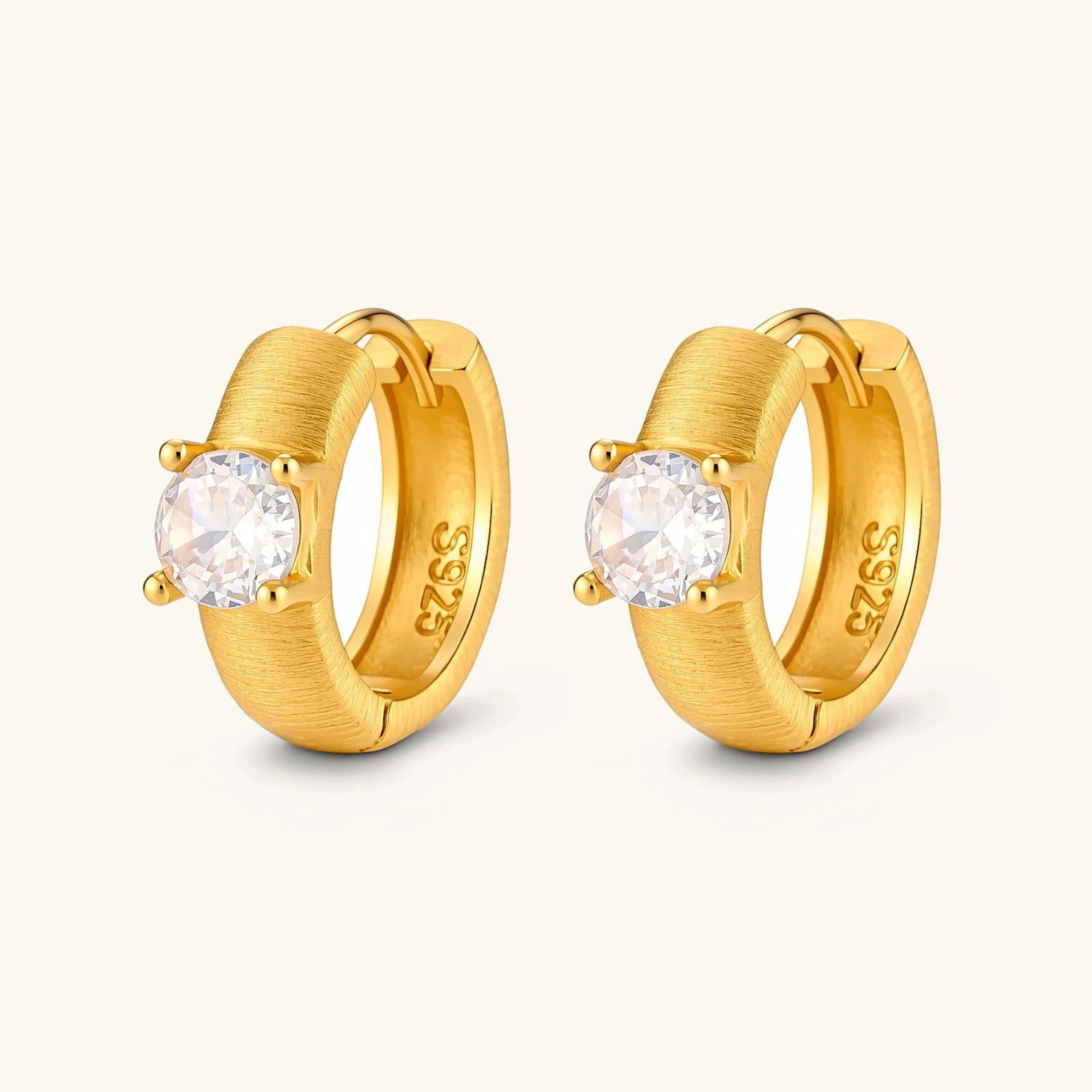 18K gold-plated 925 silver huggie hoops with brushed finish and prong-set round CZ solitaire, stamped S925 inside.